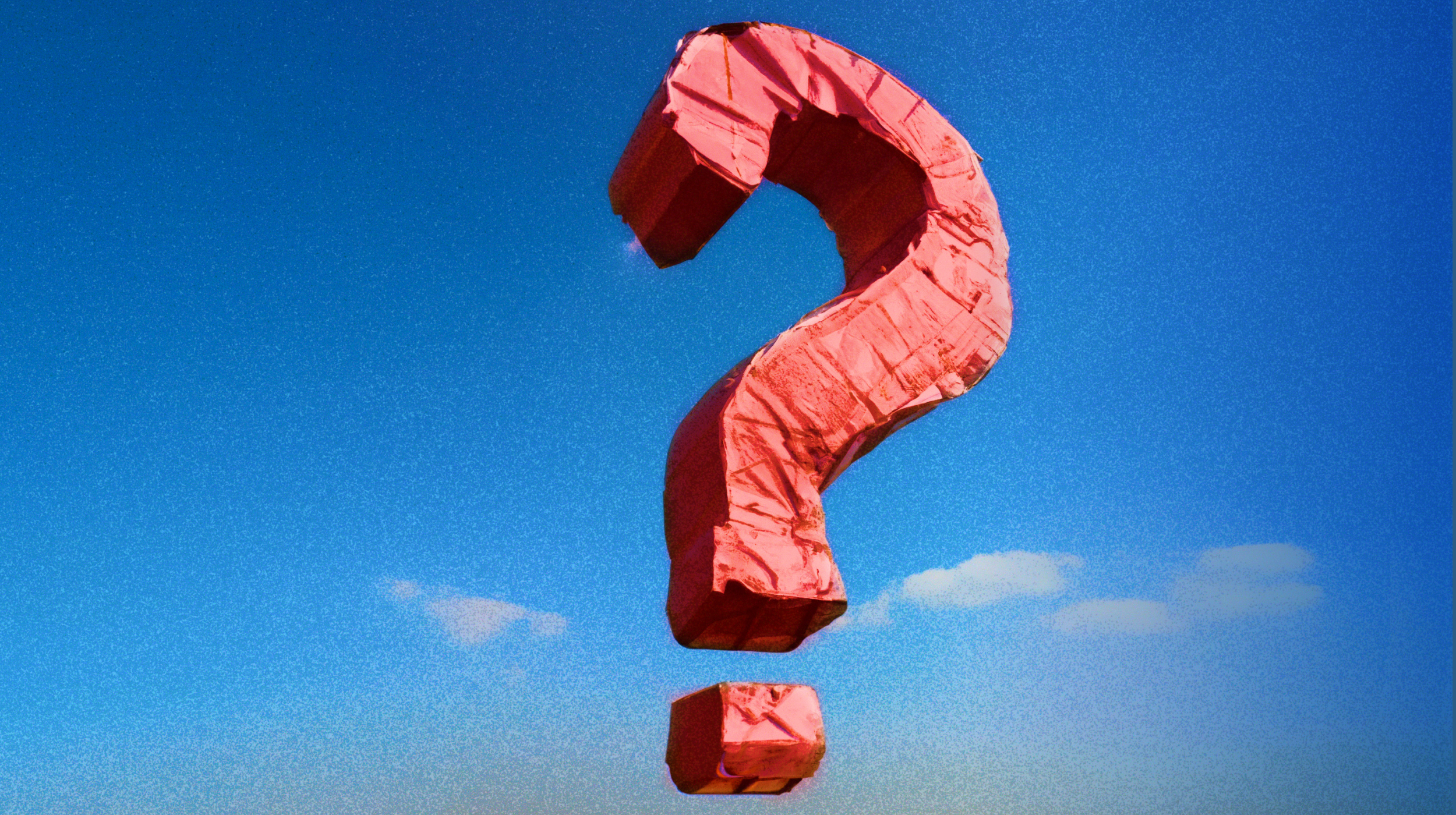 a red question mark kite flying in the sky.